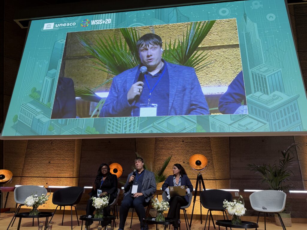 Kolm panelisti laval, jakob keskel, tema kõrval kaks naisterahvast.
Taustal palmipuud.
Lava kohal on ekraan, kus näidatakse samuti jakobit.Ekraani ülaosas kiri unesco”